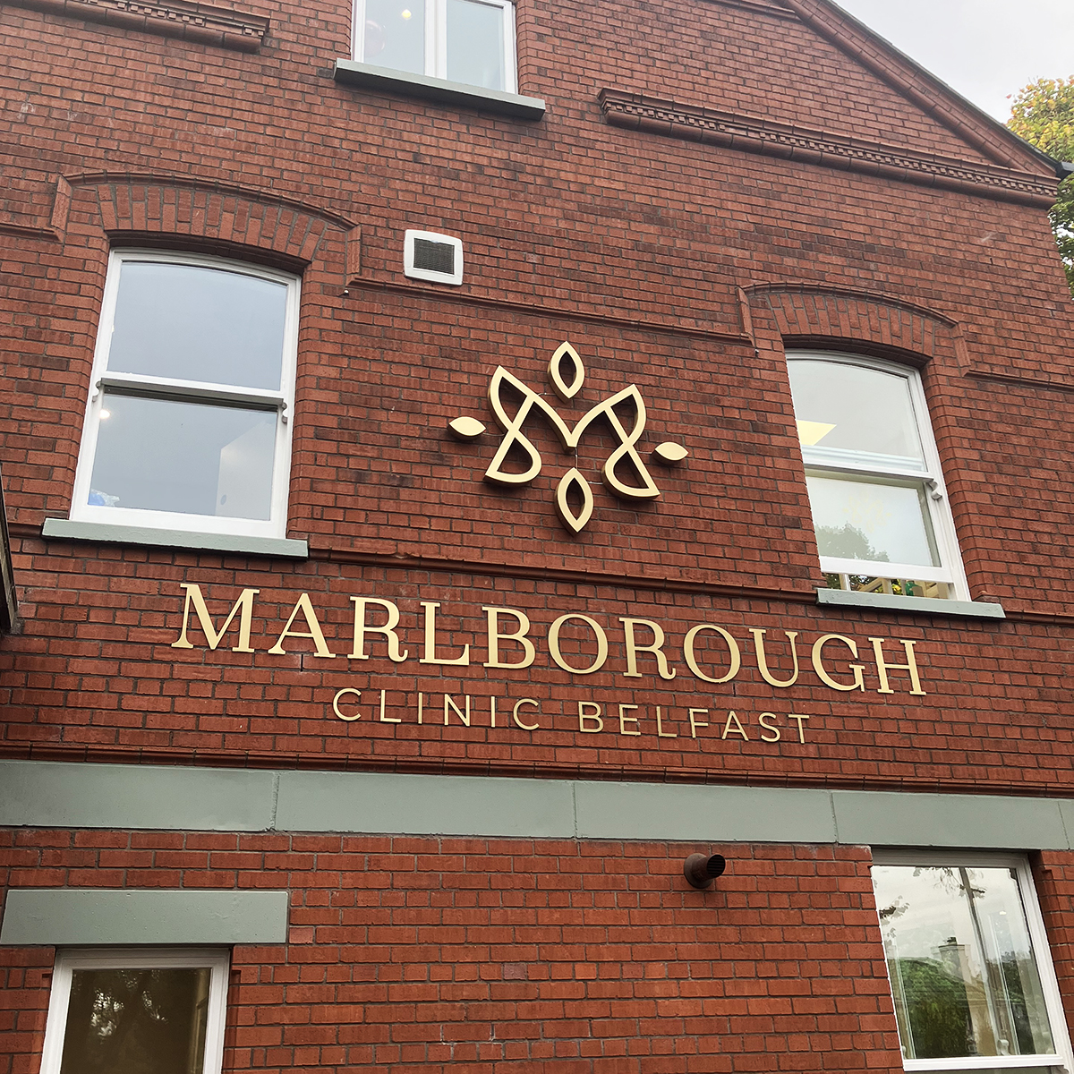 Red brick building with brushed gold stainless-steel Marlborough Clinic Belfast logo and letters