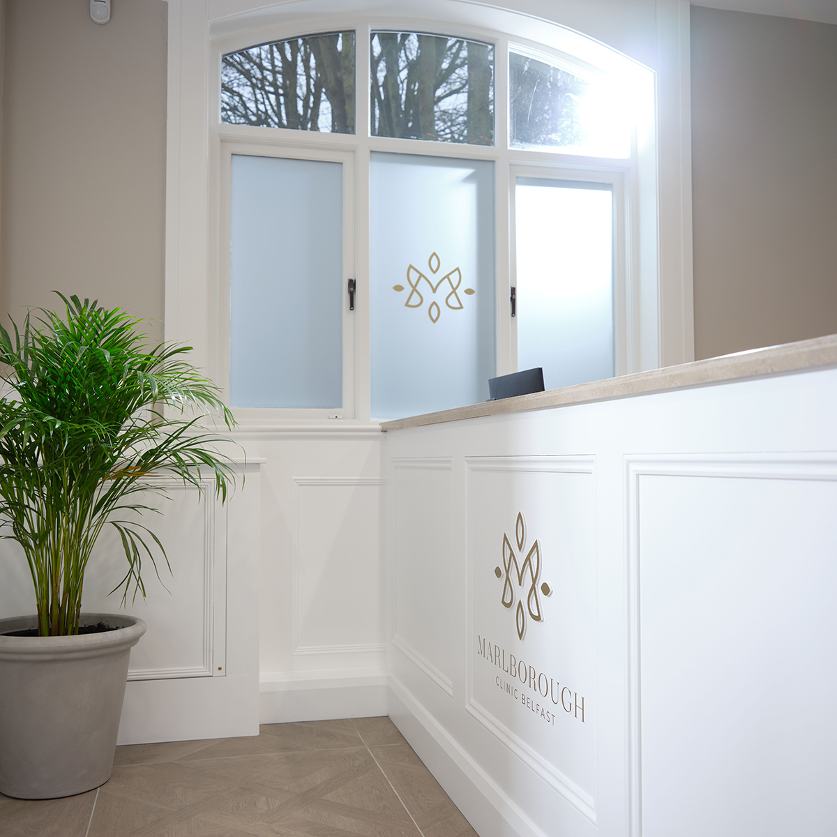 Gold Marlborough Clinic Belfast logo on white reception desk and frosted window